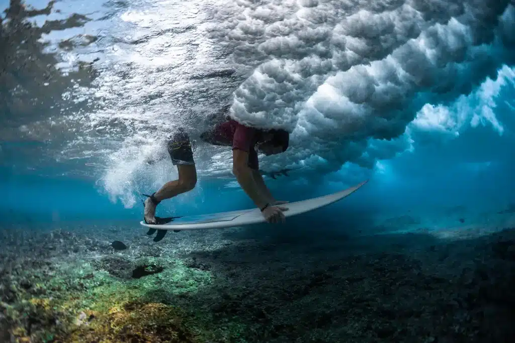 Surfeur faisant un canard sur une vague avec peu de fond à Bali