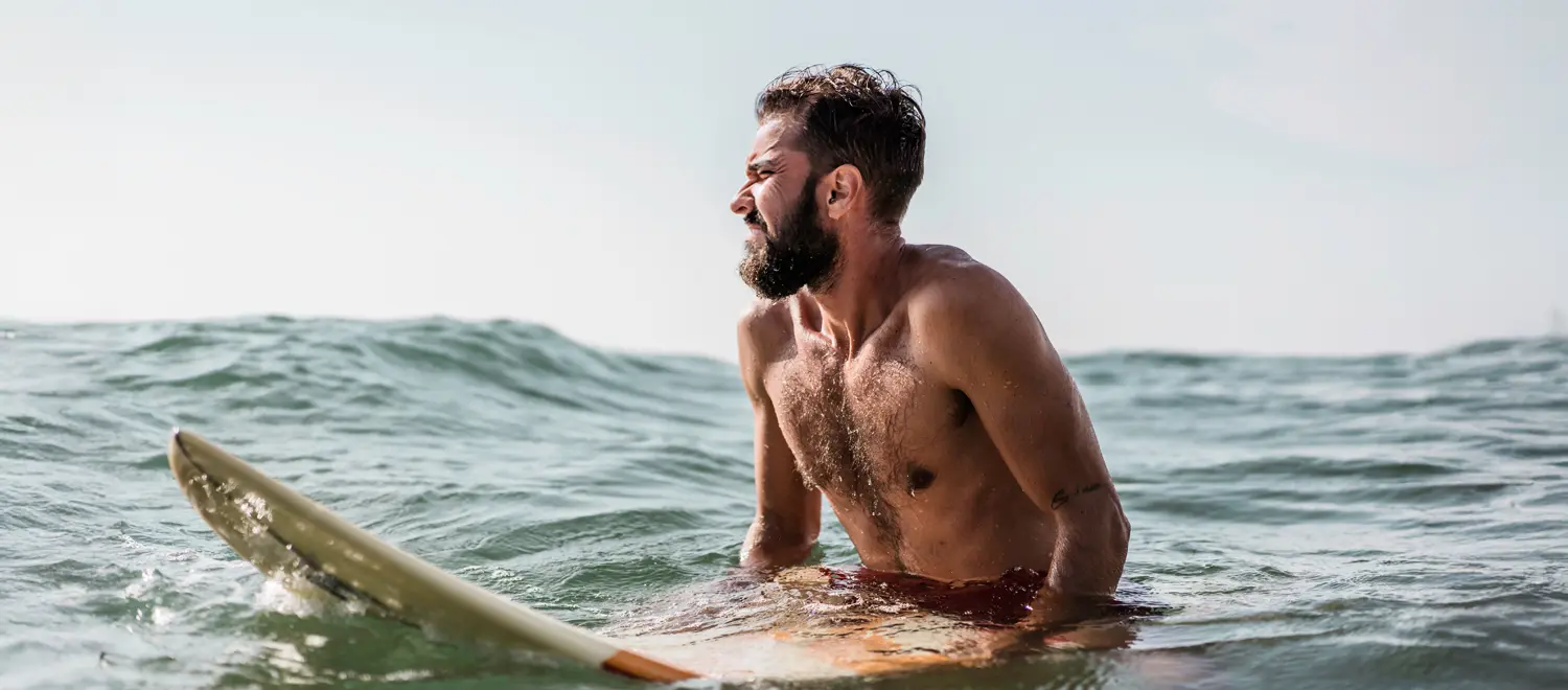 Surfeur victime du Bali belly pendant qu'il attend une vague à Bali